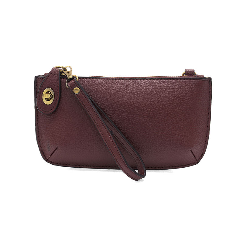 Maroon leather clutch with a strap on a white background