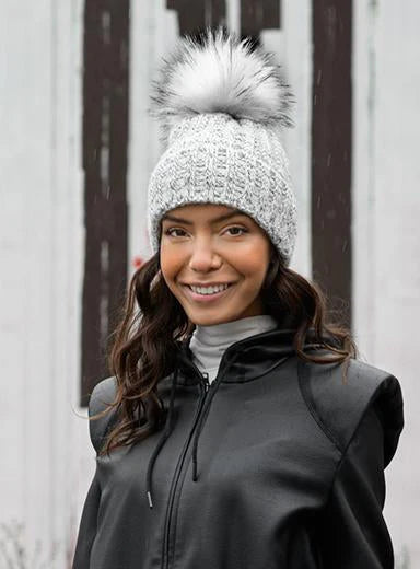 Woman wearing a textured knit beanie with a pom-pom outdoors