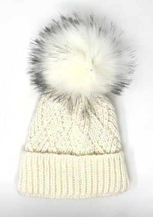White knit beanie with a large faux fur pom-pom on a white background