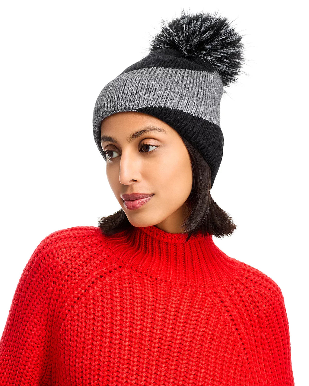 Person wearing a gray and black striped beanie with a pom-pom, on a white background