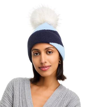 Woman wearing a blue and navy beanie with a white pom-pom on a white background
