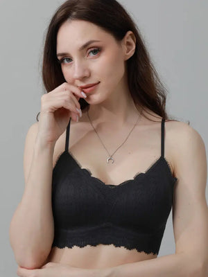 Woman wearing a black lace bralette against a gray background