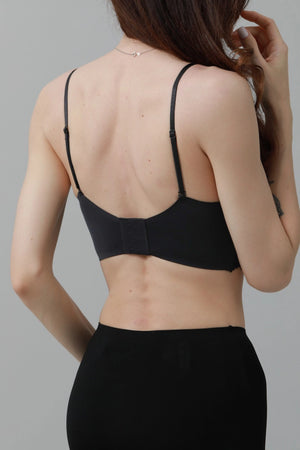Person wearing a black bralette against a gray background