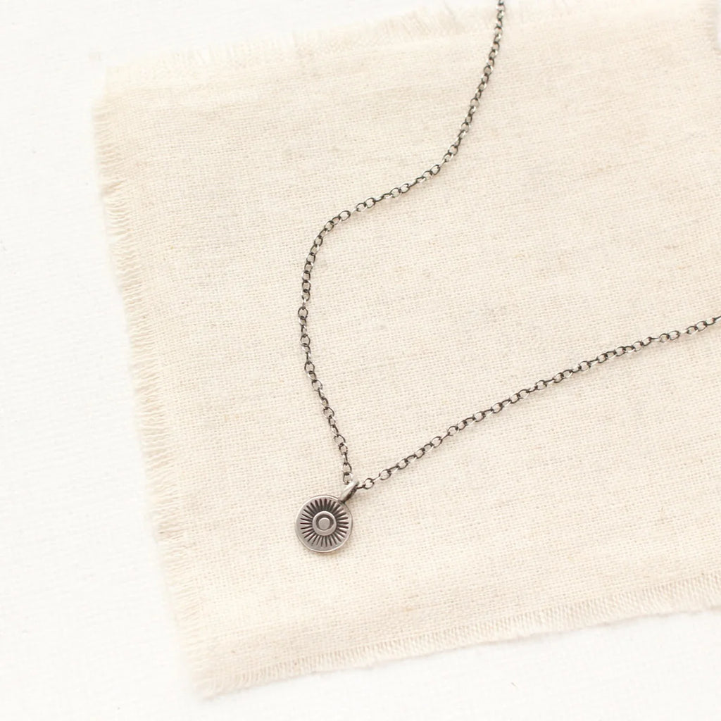 Good things come in small packages. A tiny stamped sun hangs on a silver chain. An easy everyday look. Chain measures 17-18” with lobster clasp and adjustable length chain closure. Sterling silver, which has been oxidized and hand polished for an antique finish.