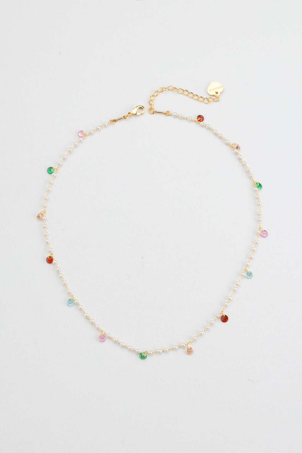 Elevate your elegance with the Nakamol Kindness necklace, featuring a delicate strand of lustrous white pearls accented by vibrant multi-color stone dangles. This refined piece adds a subtle yet striking splash of color, perfect for enhancing both formal and everyday ensembles with timeless sophistication.