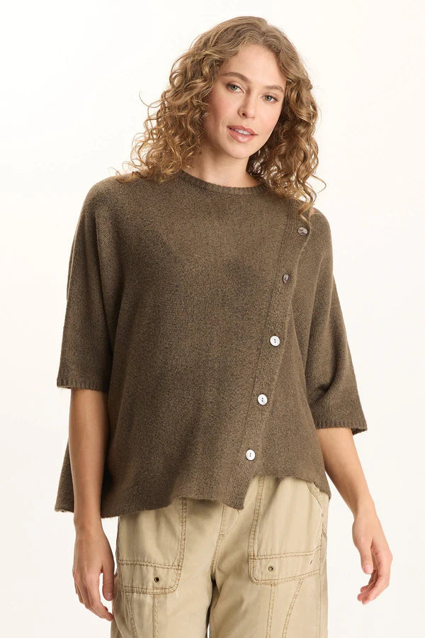 Woman wearing a brown button-up sweater over a beige shirt on a white background