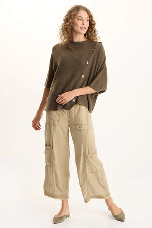 Woman wearing a brown poncho and beige cargo pants on a white background