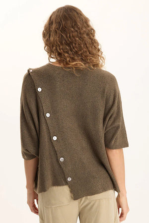 Person wearing a brown cardigan with button details on a white background