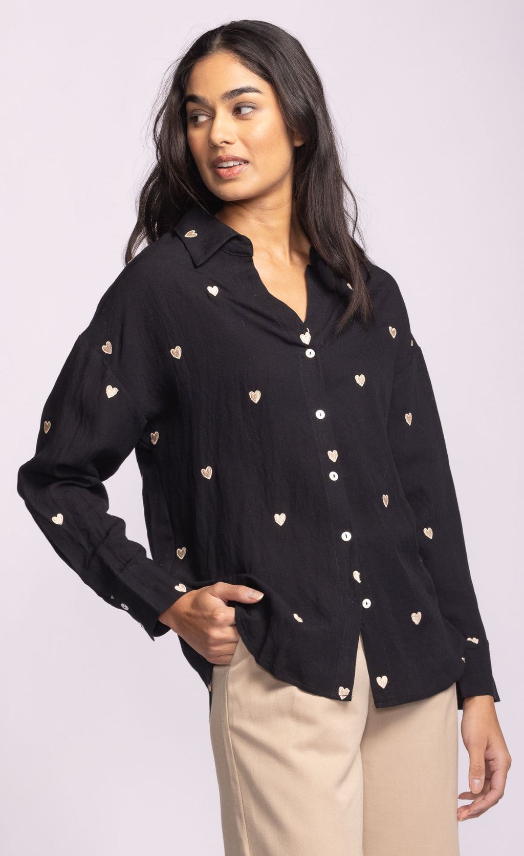 Woman wearing a black shirt with heart patterns on a light purple background