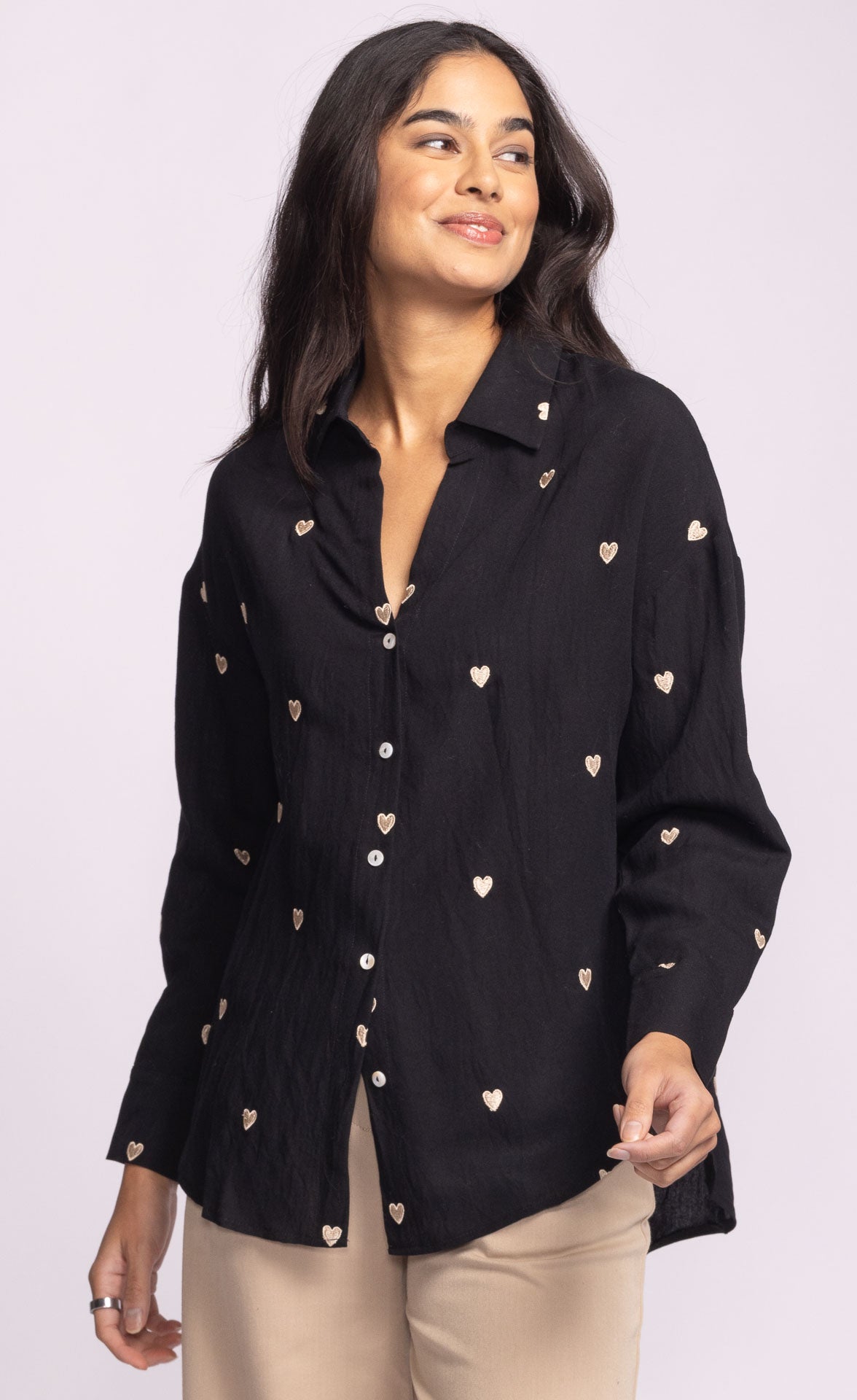 Woman wearing a black shirt with heart patterns on a light purple background