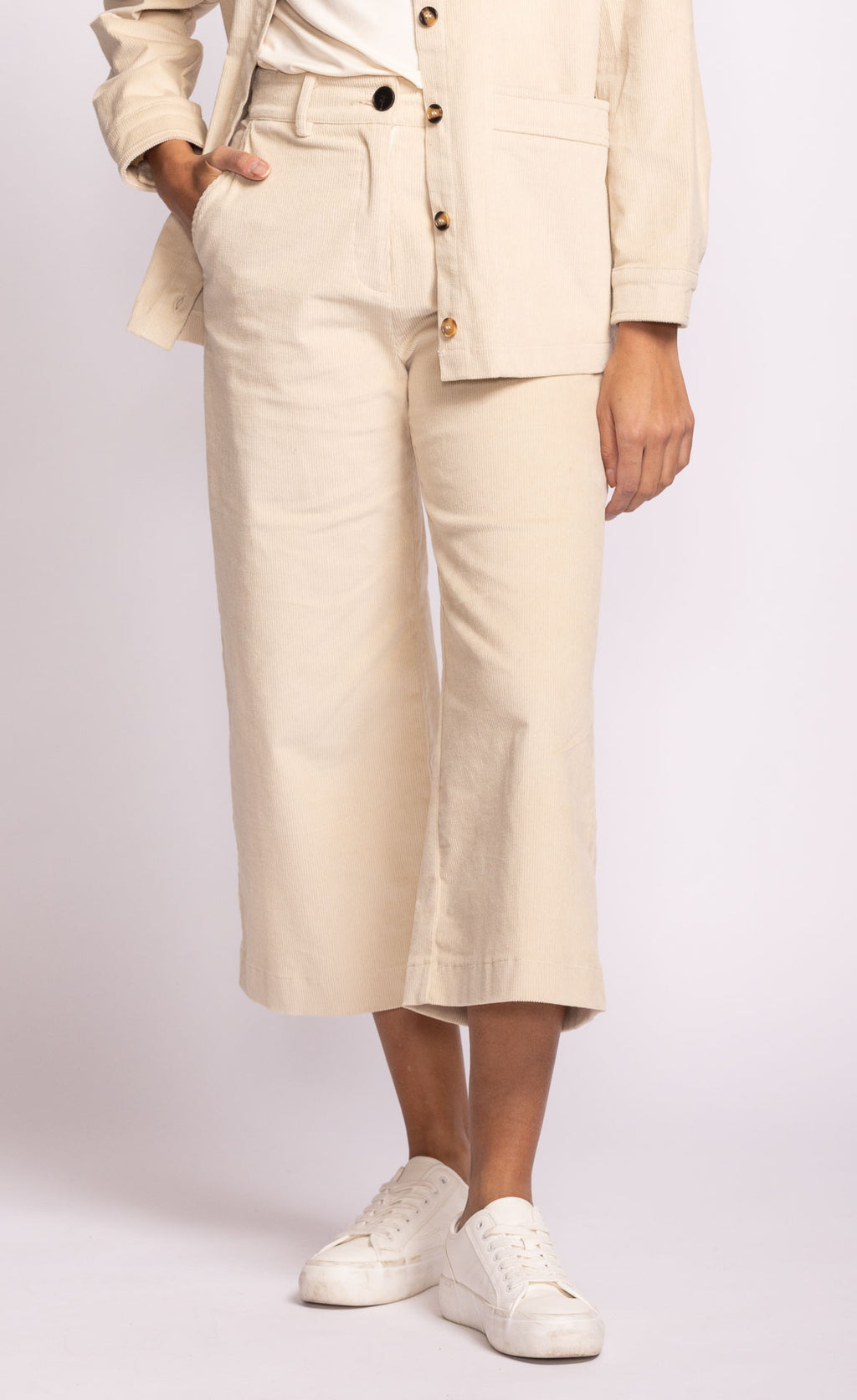 Person wearing a beige suit with cropped pants on a white background