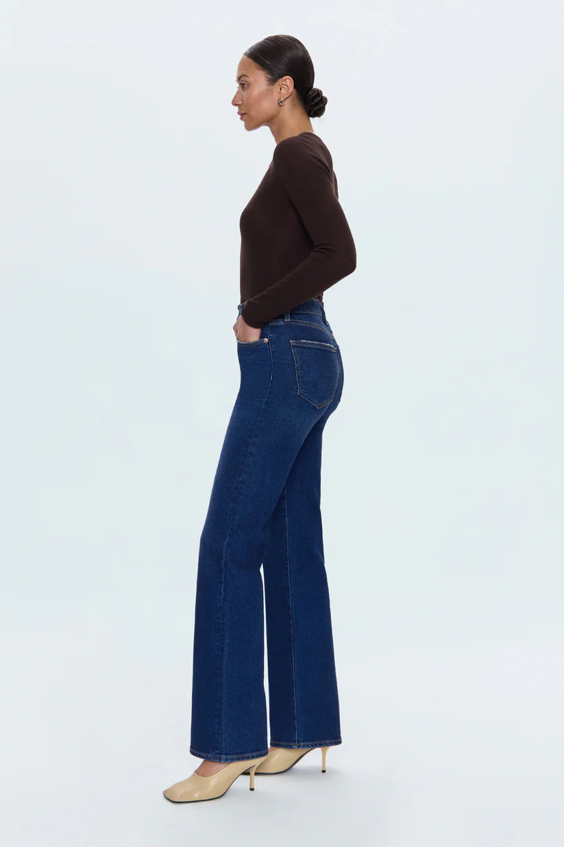 Woman wearing blue jeans and a brown top on a white background