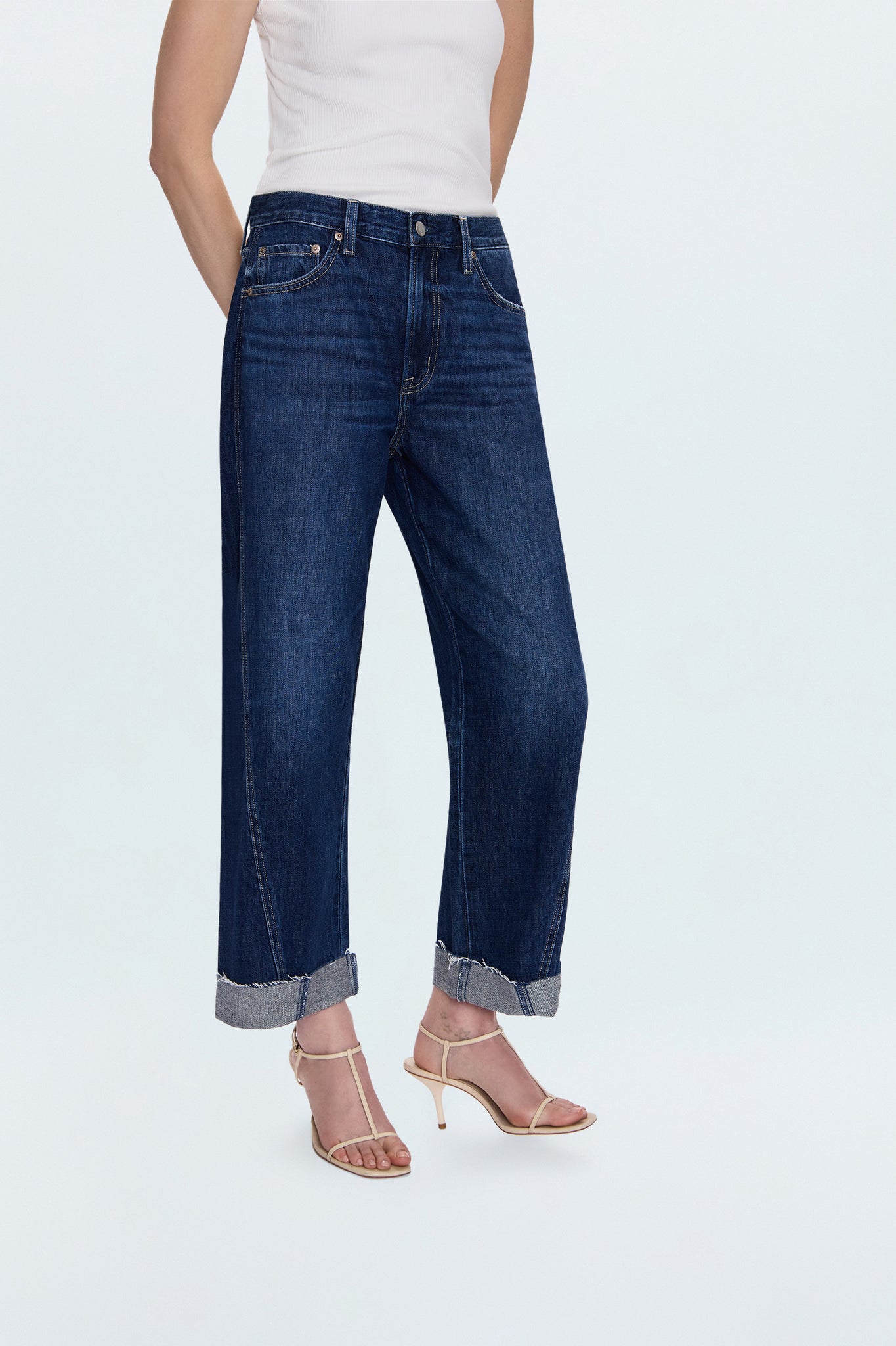 Person wearing dark blue jeans and a white top on a light gray background