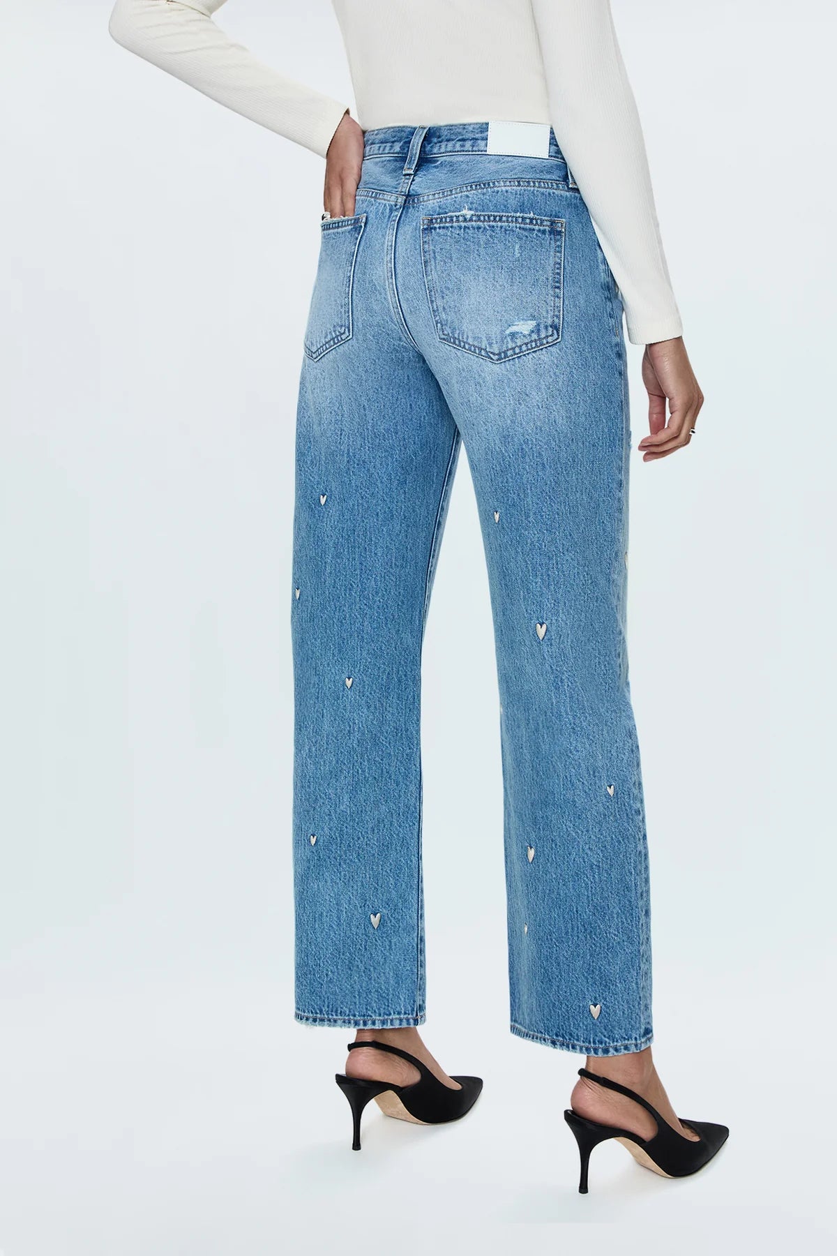 Mid-rise, straight leg with a subtle bow at the thigh and knee for an elevated barrel leg silhouette. Ankle length crop with a clean finish hem, crafted from rigid non-stretch denim for an expert fit that holds its shape. Confetti Vintage is a medium blue wash adorned with an embroidered heart motif throughout and minor hints of distressing.