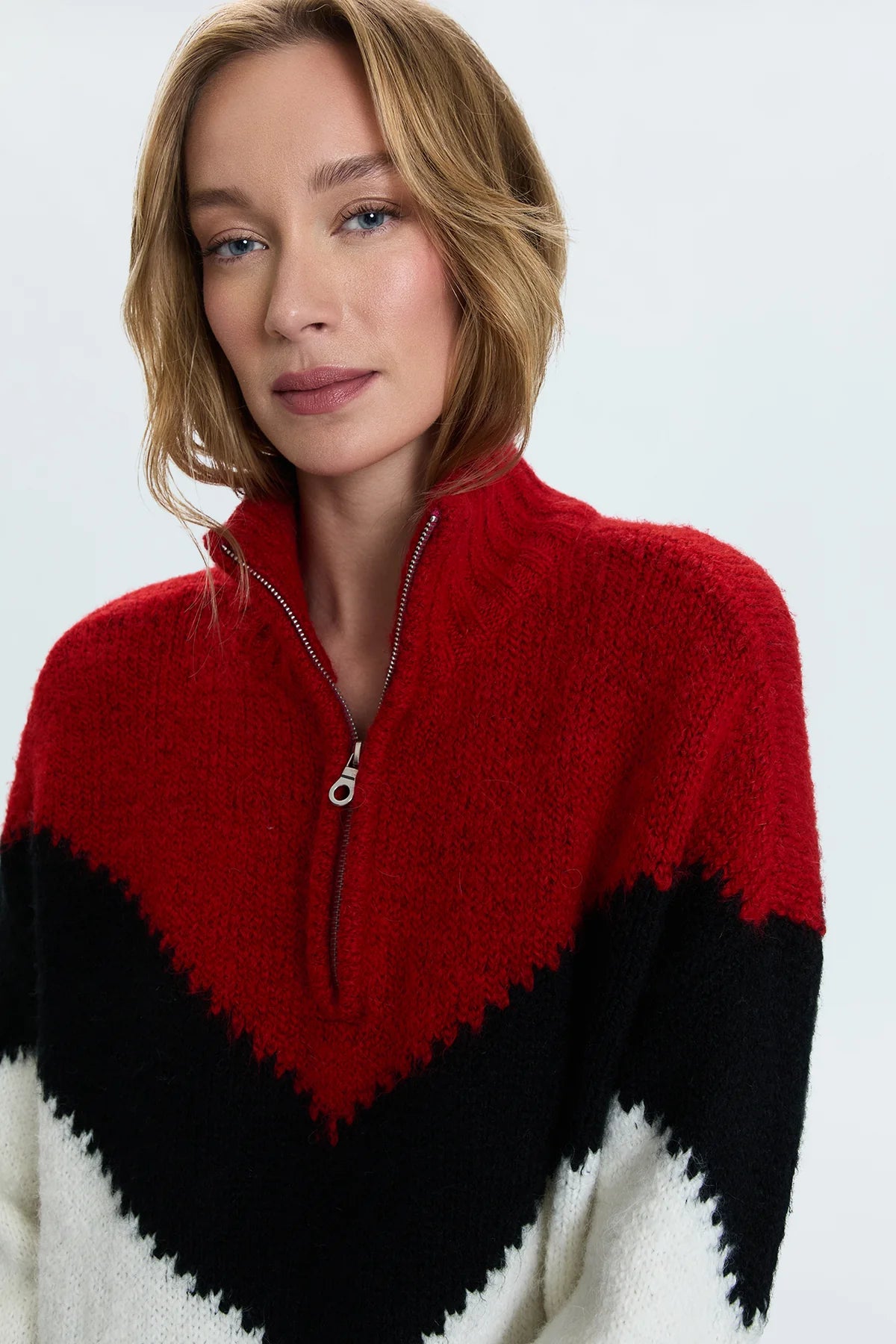 Medium weight pullover sweater with a relaxed pullover fit. With a quarter zip neckline and high sport collar. Lofty ribbing at cuffs and hem. Offered in a multi-colored red and black chevron motif over a cream white base hue.