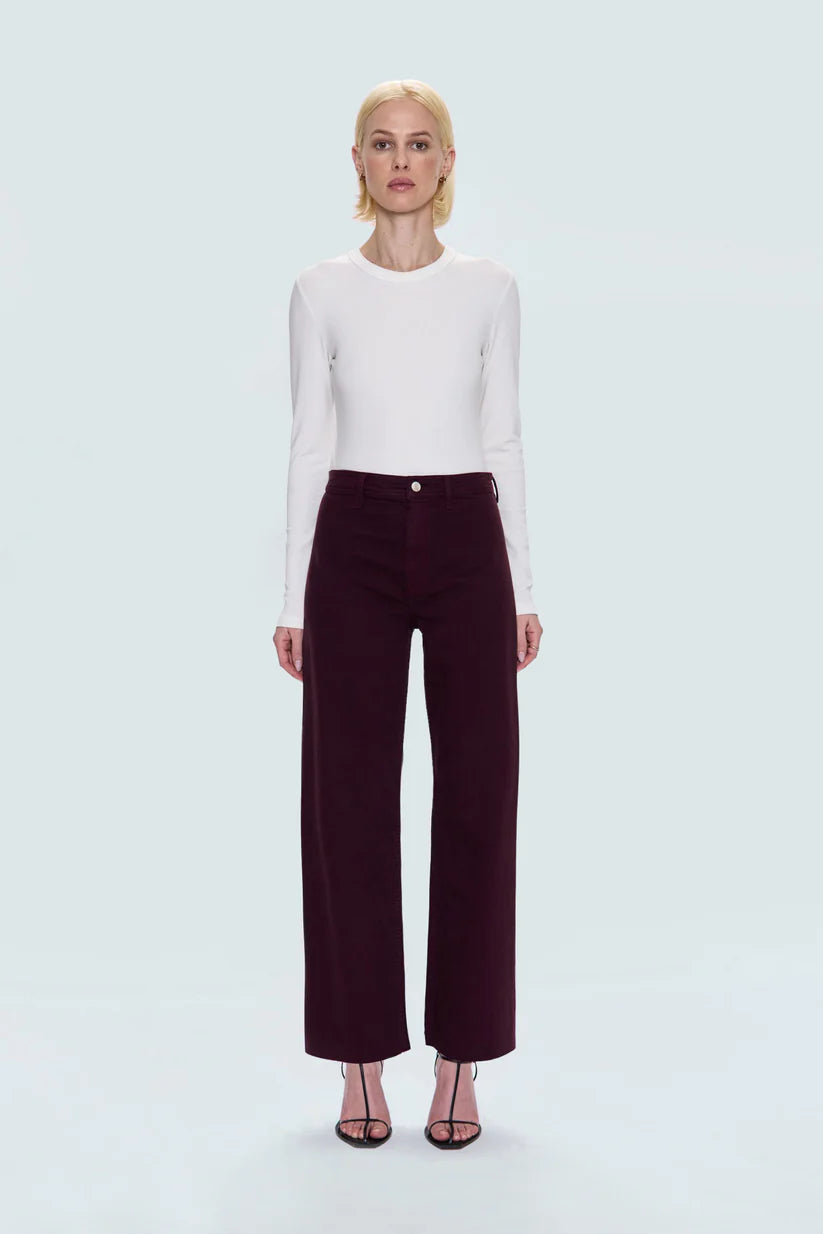 Person wearing a white long-sleeve top and burgundy pants on a light gray background
