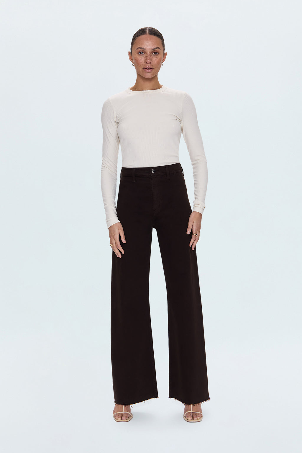 Woman wearing a white sweater and black pants on a white background
