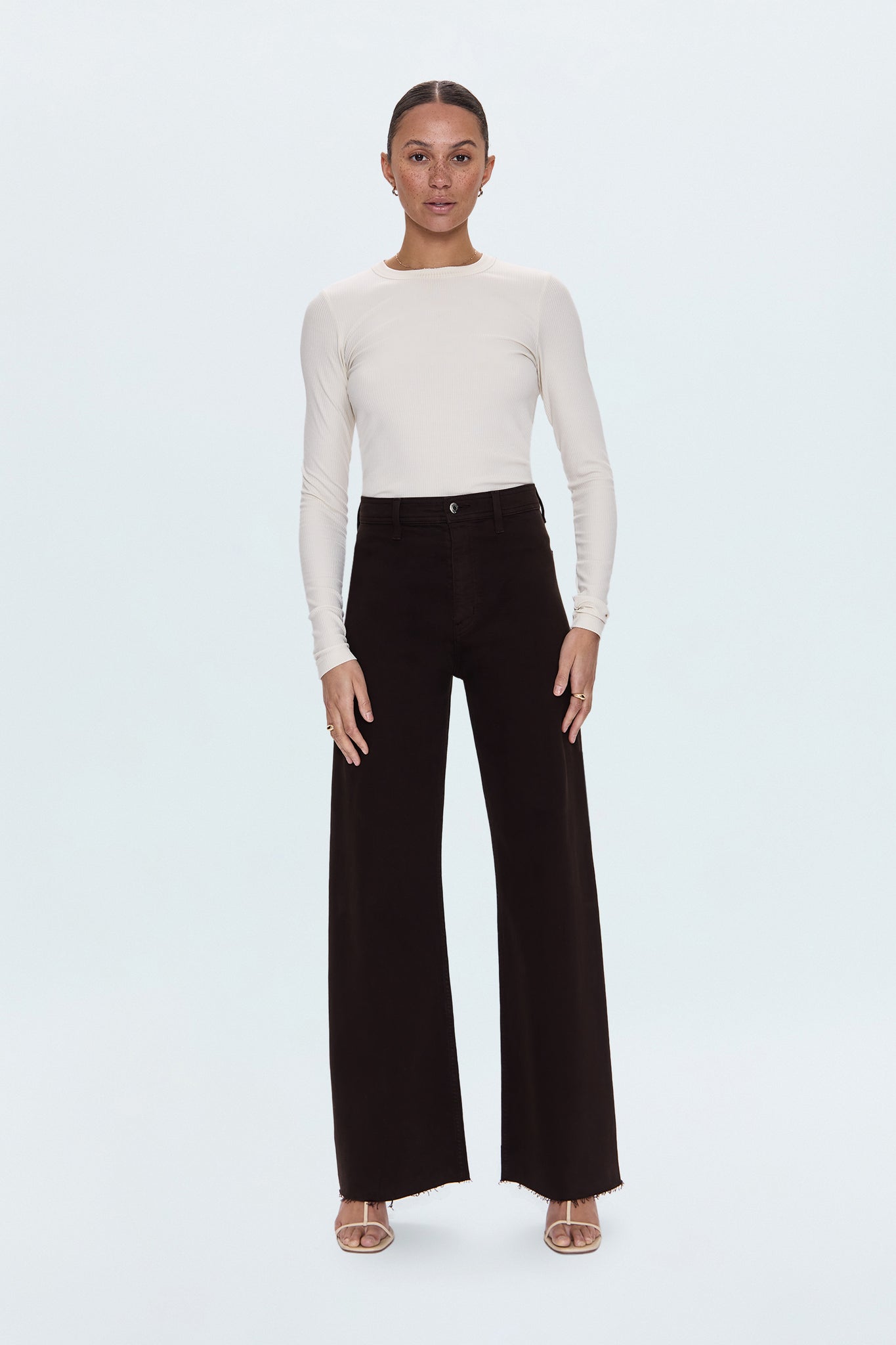 Woman wearing a white sweater and black pants on a white background