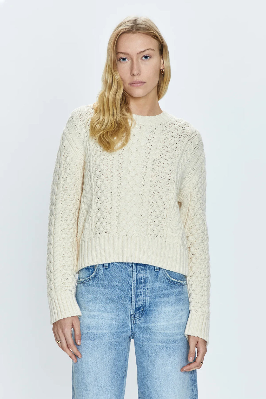 Crewneck pullover sweater with a relaxed, shrunken silhouette. Crafted with mixed cable open knit-work for textural dimension and medium weight wearability. Finished with single layer ribbed neckline, hem, and cuffs and offered in a warm, ivory colorway.