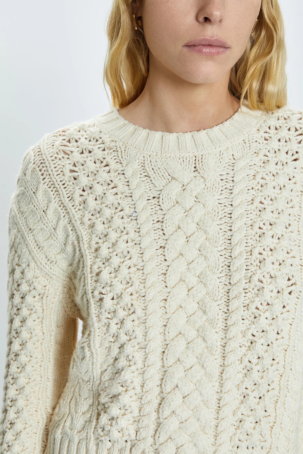 Crewneck pullover sweater with a relaxed, shrunken silhouette. Crafted with mixed cable open knit-work for textural dimension and medium weight wearability. Finished with single layer ribbed neckline, hem, and cuffs and offered in a warm, ivory colorway.