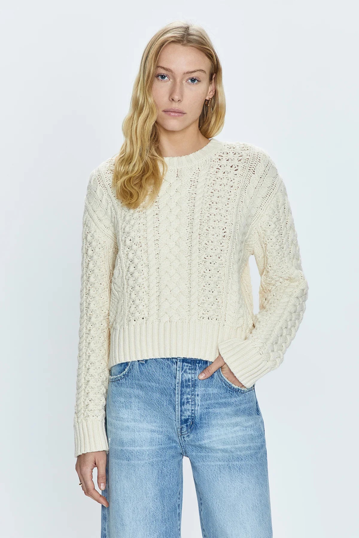 Crewneck pullover sweater with a relaxed, shrunken silhouette. Crafted with mixed cable open knit-work for textural dimension and medium weight wearability. Finished with single layer ribbed neckline, hem, and cuffs and offered in a warm, ivory colorway.