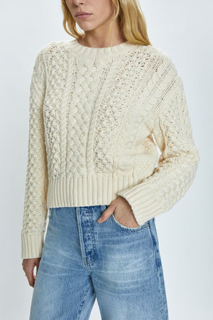 Crewneck pullover sweater with a relaxed, shrunken silhouette. Crafted with mixed cable open knit-work for textural dimension and medium weight wearability. Finished with single layer ribbed neckline, hem, and cuffs and offered in a warm, ivory colorway.