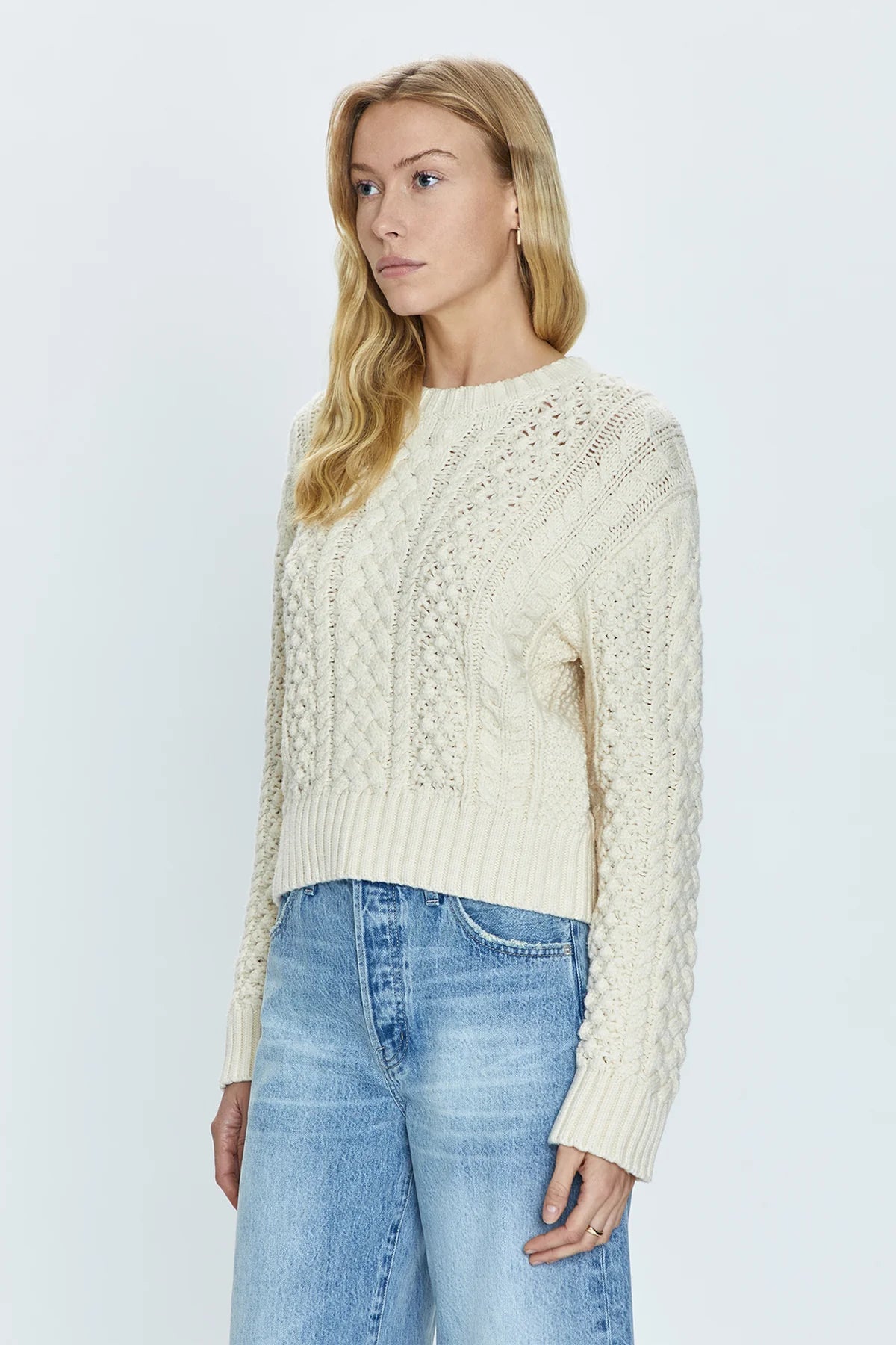 Crewneck pullover sweater with a relaxed, shrunken silhouette. Crafted with mixed cable open knit-work for textural dimension and medium weight wearability. Finished with single layer ribbed neckline, hem, and cuffs and offered in a warm, ivory colorway.