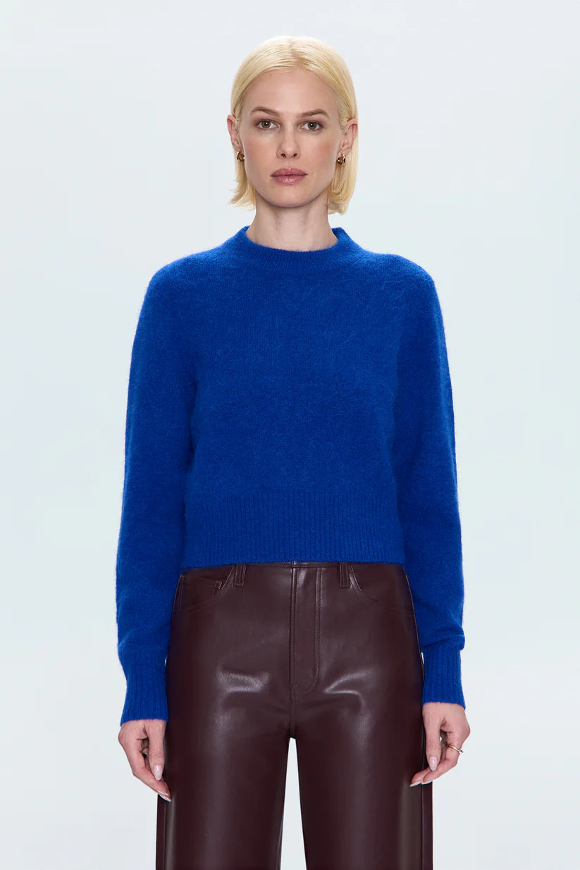 Person wearing a blue sweater and brown pants on a white background
