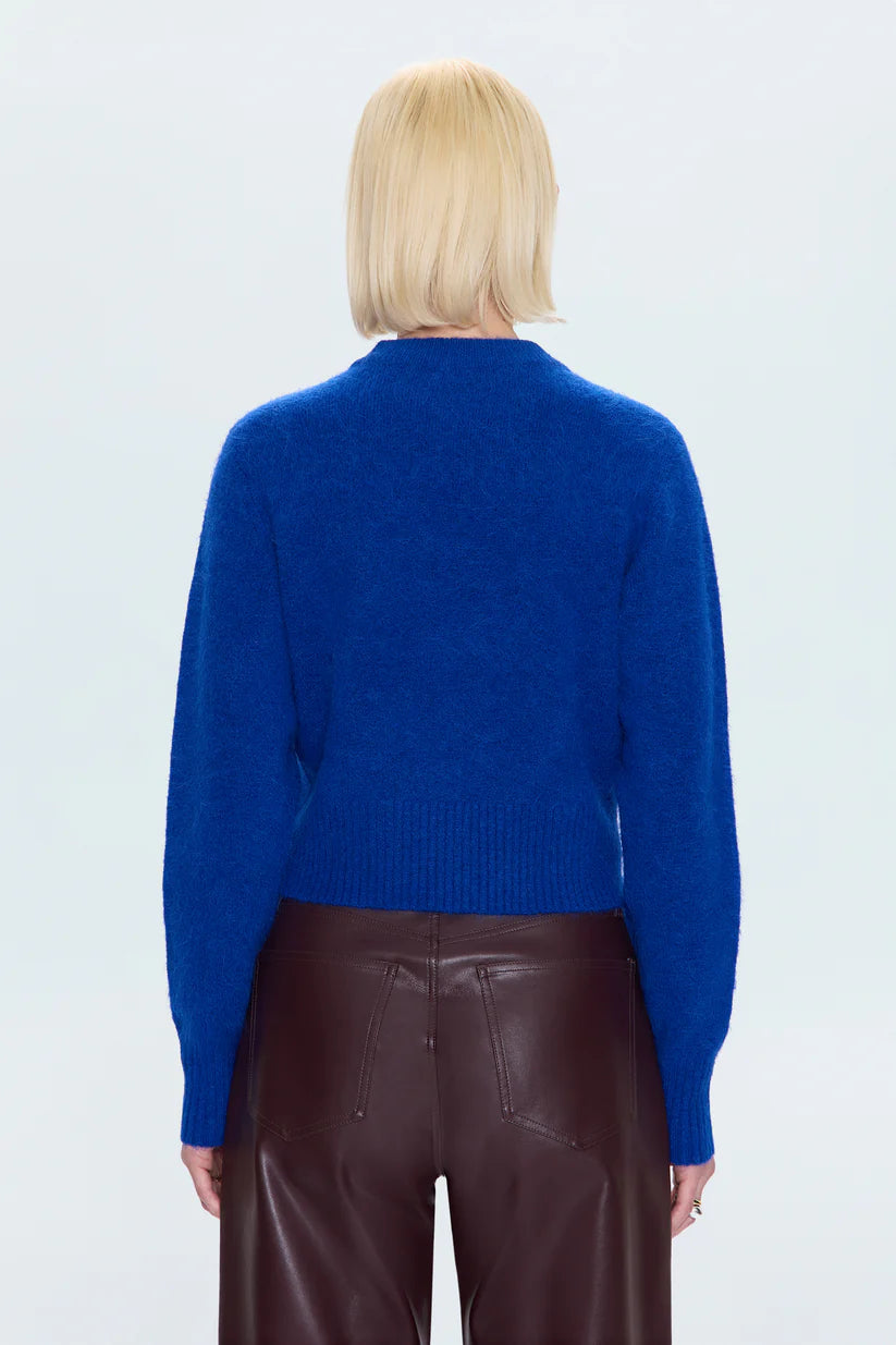 Person wearing a blue sweater and brown pants on a white background
