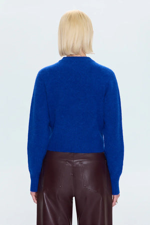 Person wearing a blue sweater and brown pants on a white background