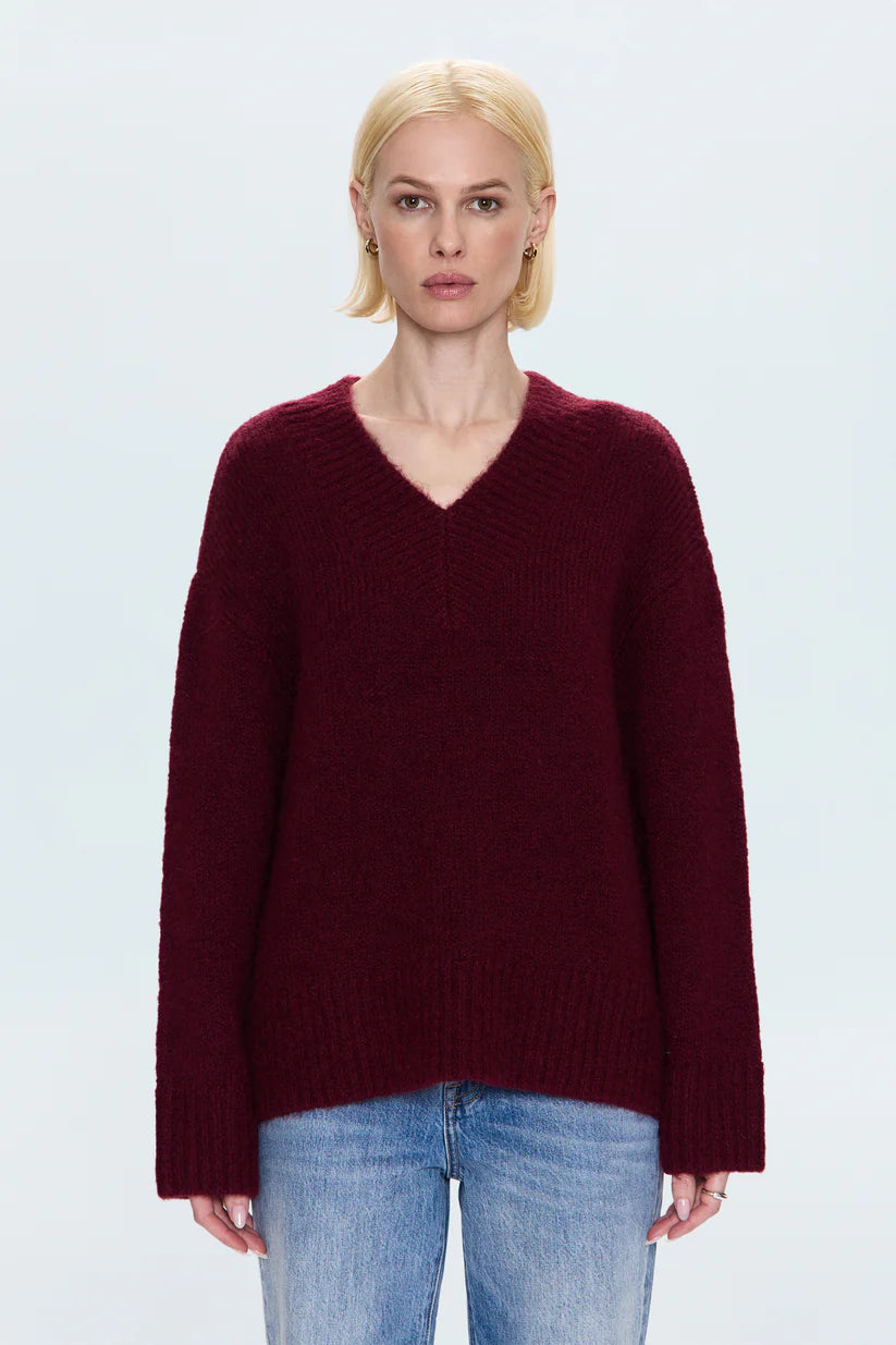 Woman wearing a burgundy sweater and light blue jeans on a white background