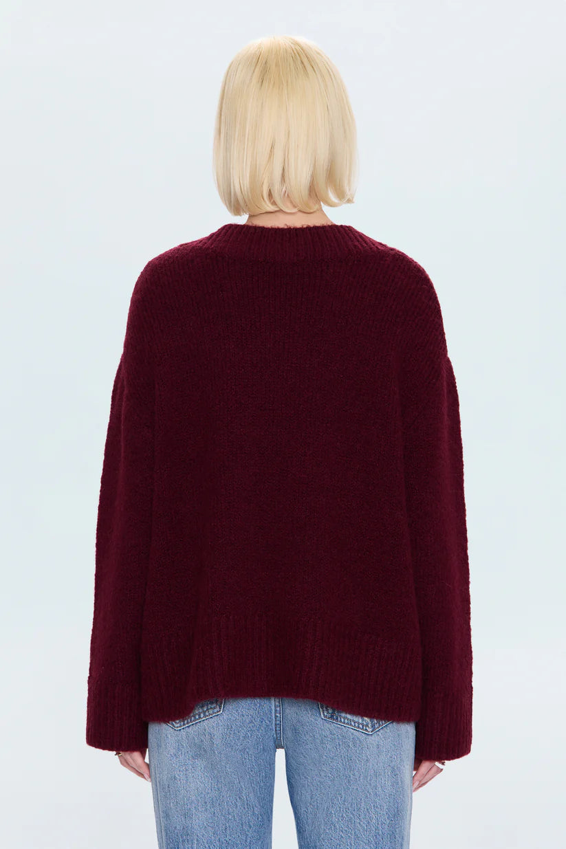 Person wearing a burgundy sweater and light blue jeans on a white background