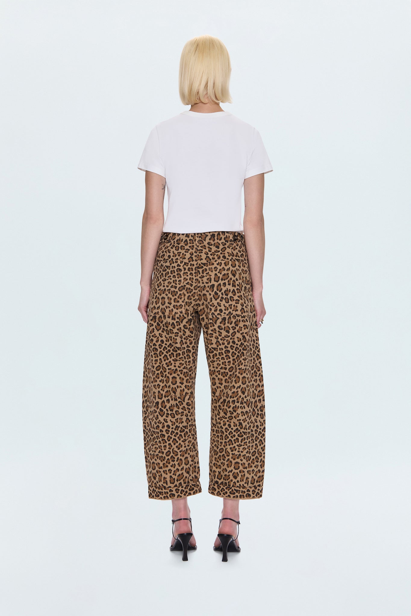 Person wearing a white t-shirt and leopard print pants on a white background