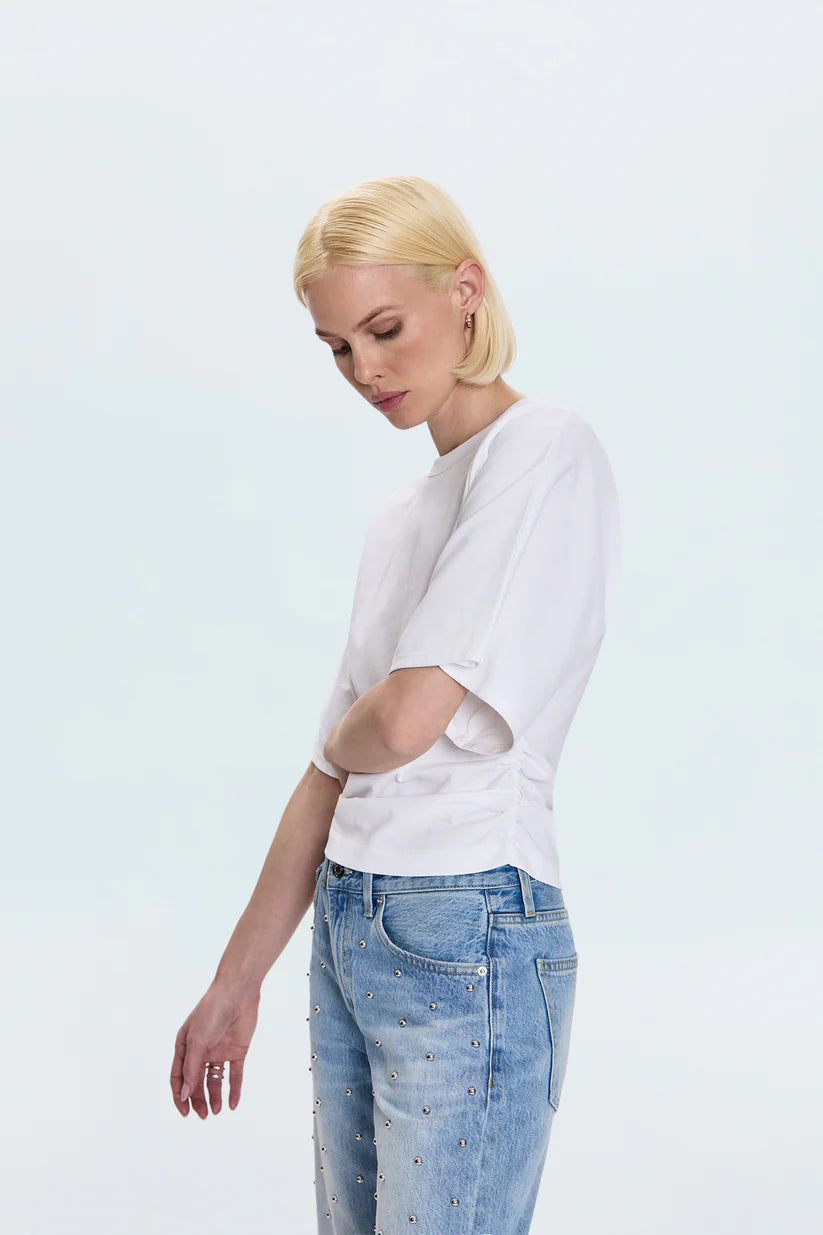 Woman wearing a white t-shirt and light blue jeans on a light gray background