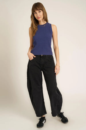 Woman wearing a blue sleeveless top and black pants on a white background