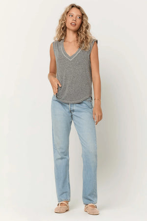 Woman wearing a gray sleeveless top and light blue jeans against a white background