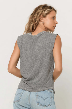 Woman wearing a gray sleeveless top and light blue jeans against a white background