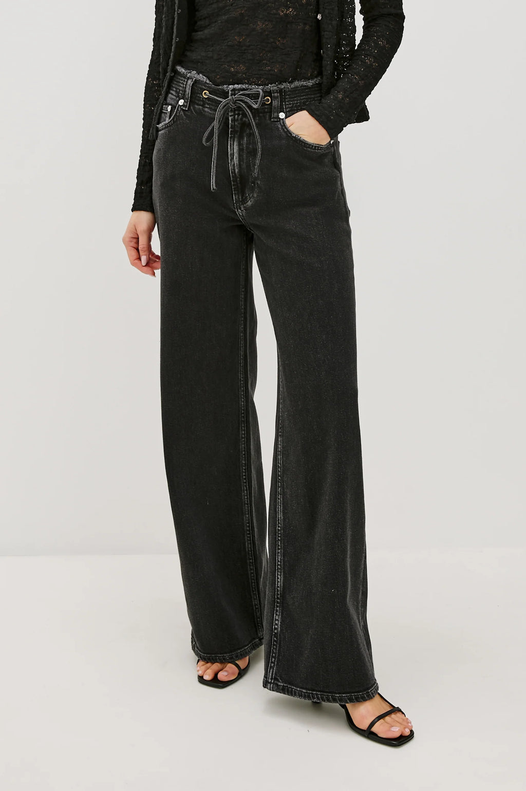 Person wearing black wide-leg jeans on a white background
