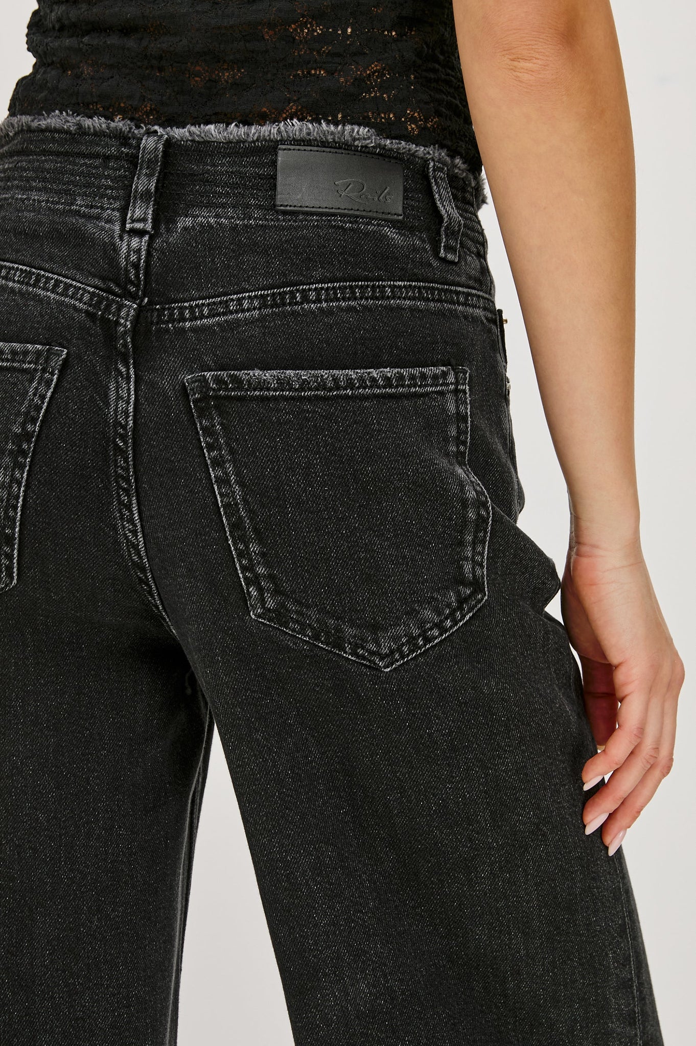Black jeans with a visible brand label on a plain background