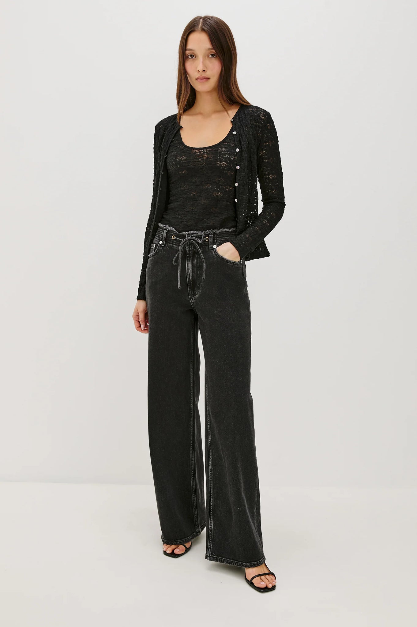 Woman wearing a black outfit with wide-leg pants on a white background