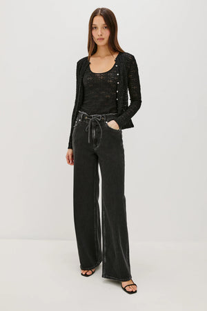 Woman wearing a black outfit with wide-leg pants on a white background