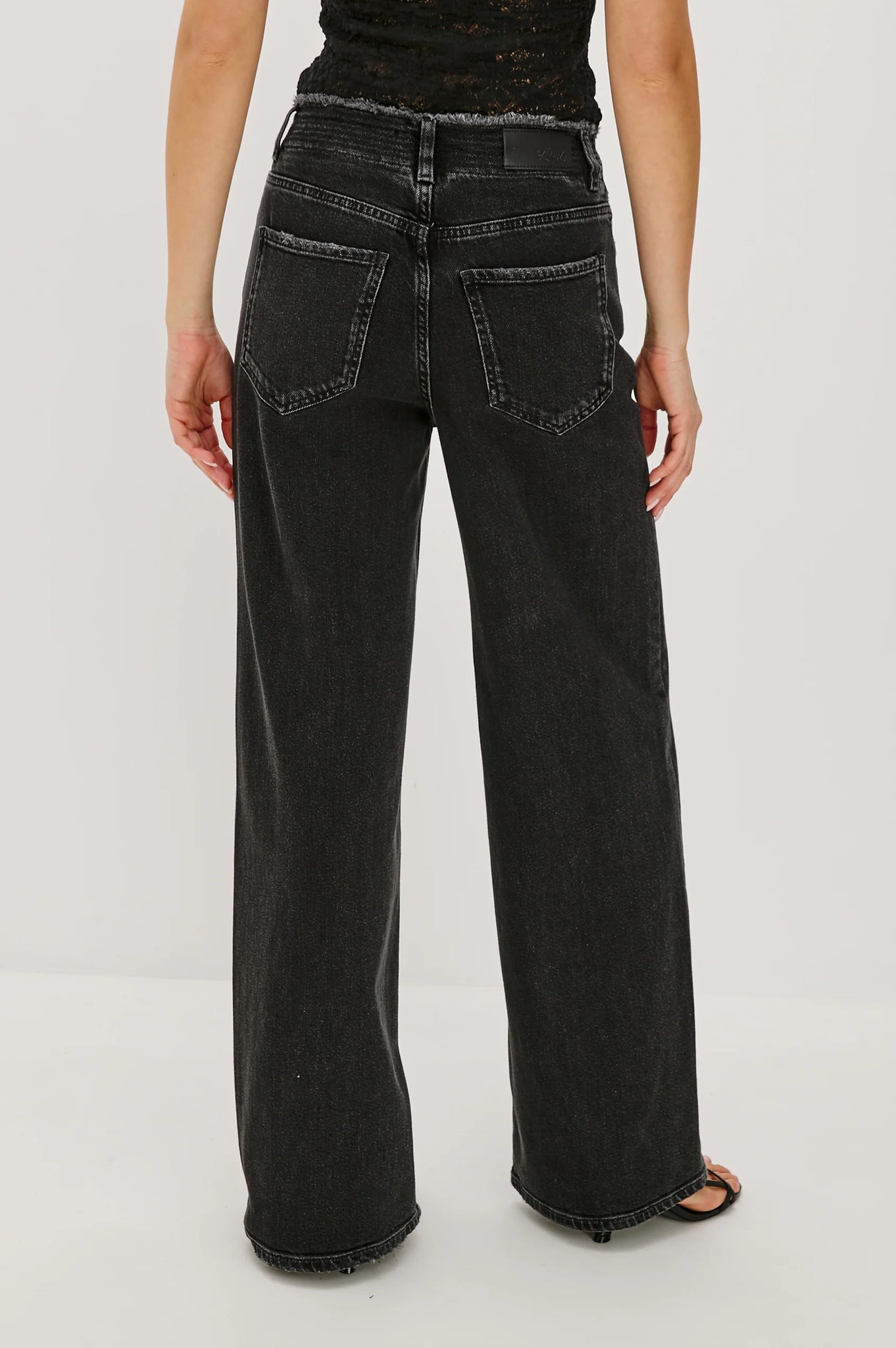 Person wearing black wide-leg jeans on a white background