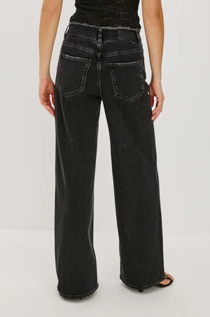 Person wearing black wide-leg jeans on a white background