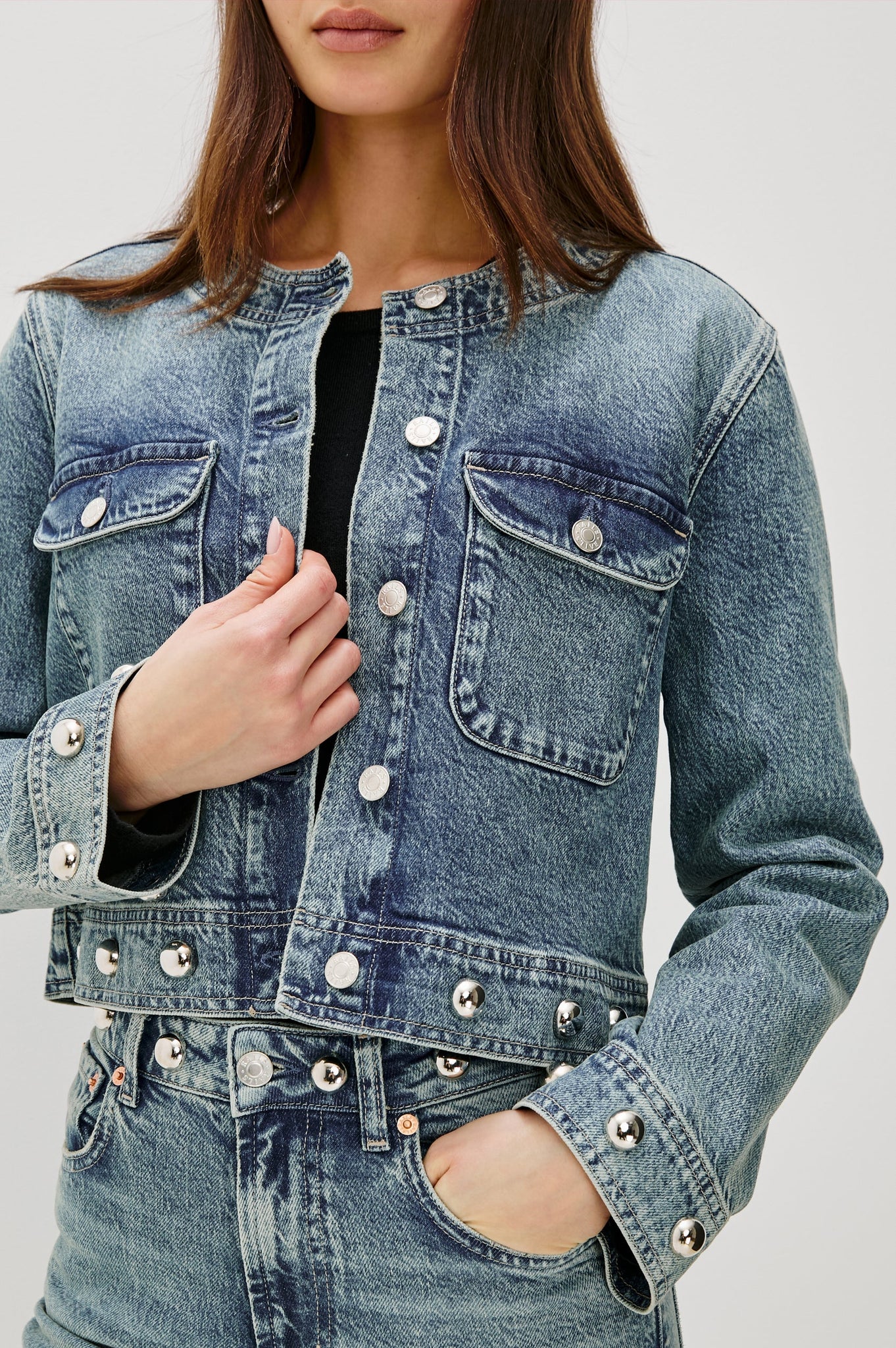 Denim jacket with button details on a plain background