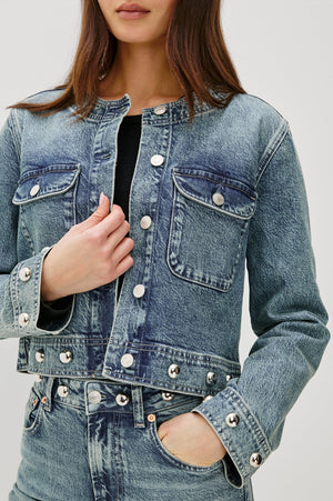 Denim jacket with button details on a plain background
