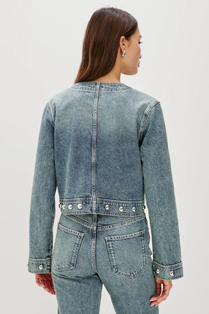 Person wearing a blue denim jacket and jeans on a white background