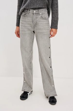 Person wearing gray jeans with decorative buttons on a white background