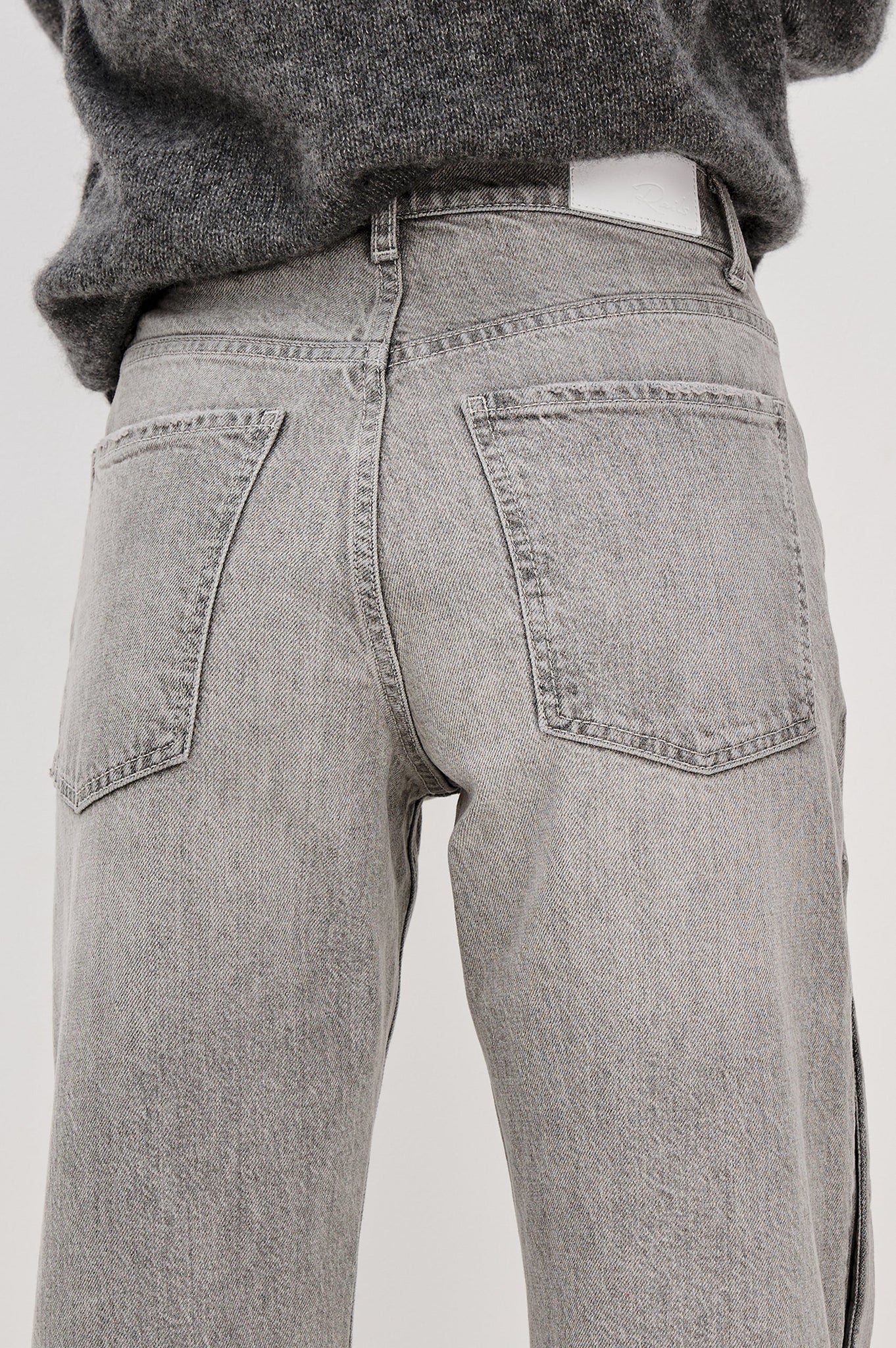 Gray jeans worn by a person on a white background