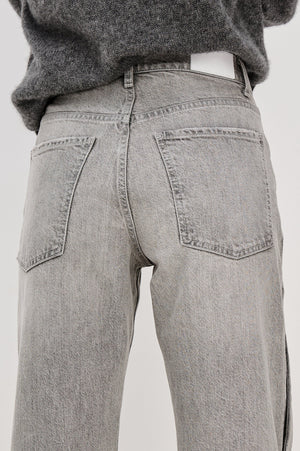 Gray jeans worn by a person on a white background