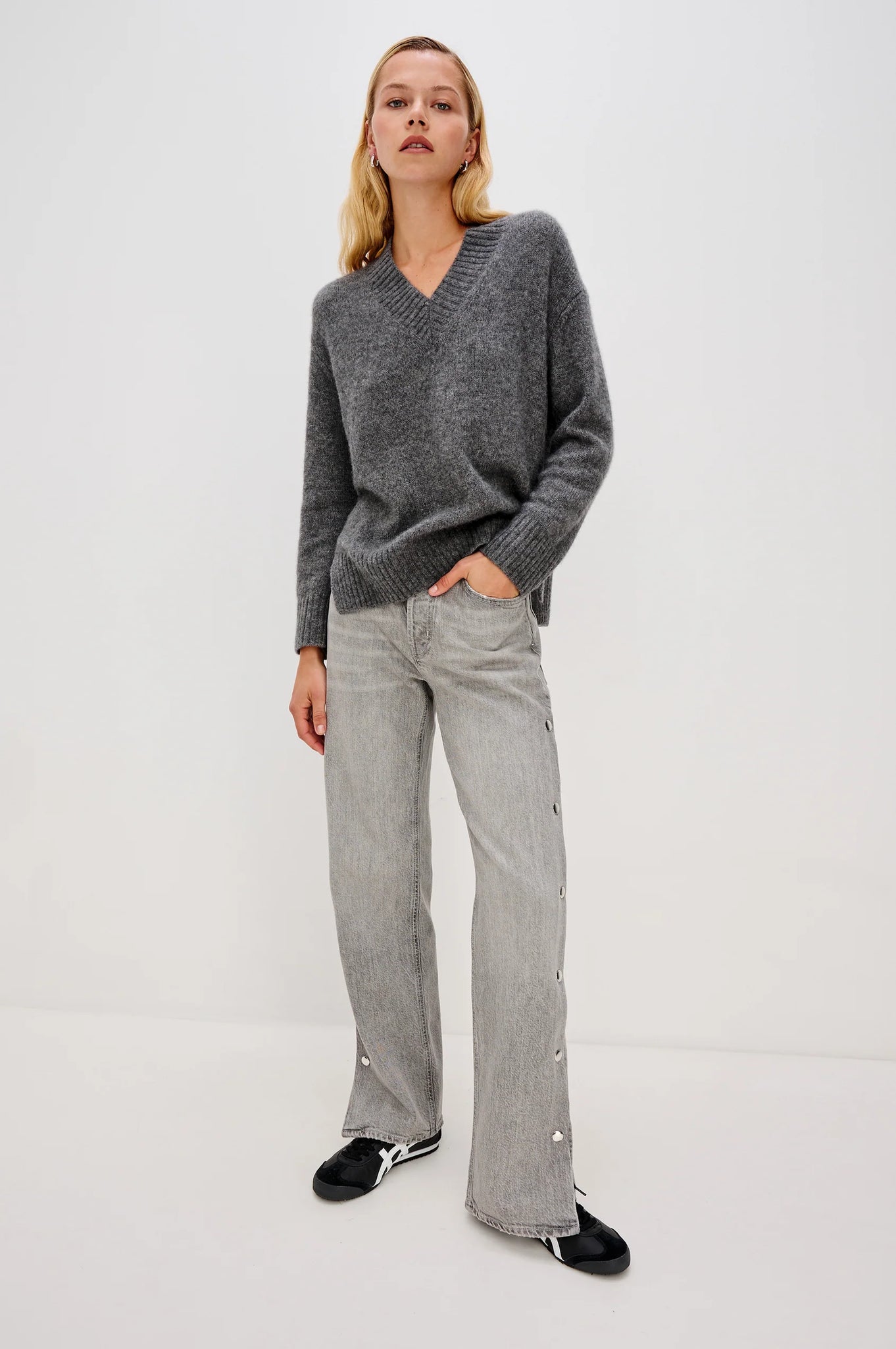 Person wearing a gray sweater and jeans on a white background